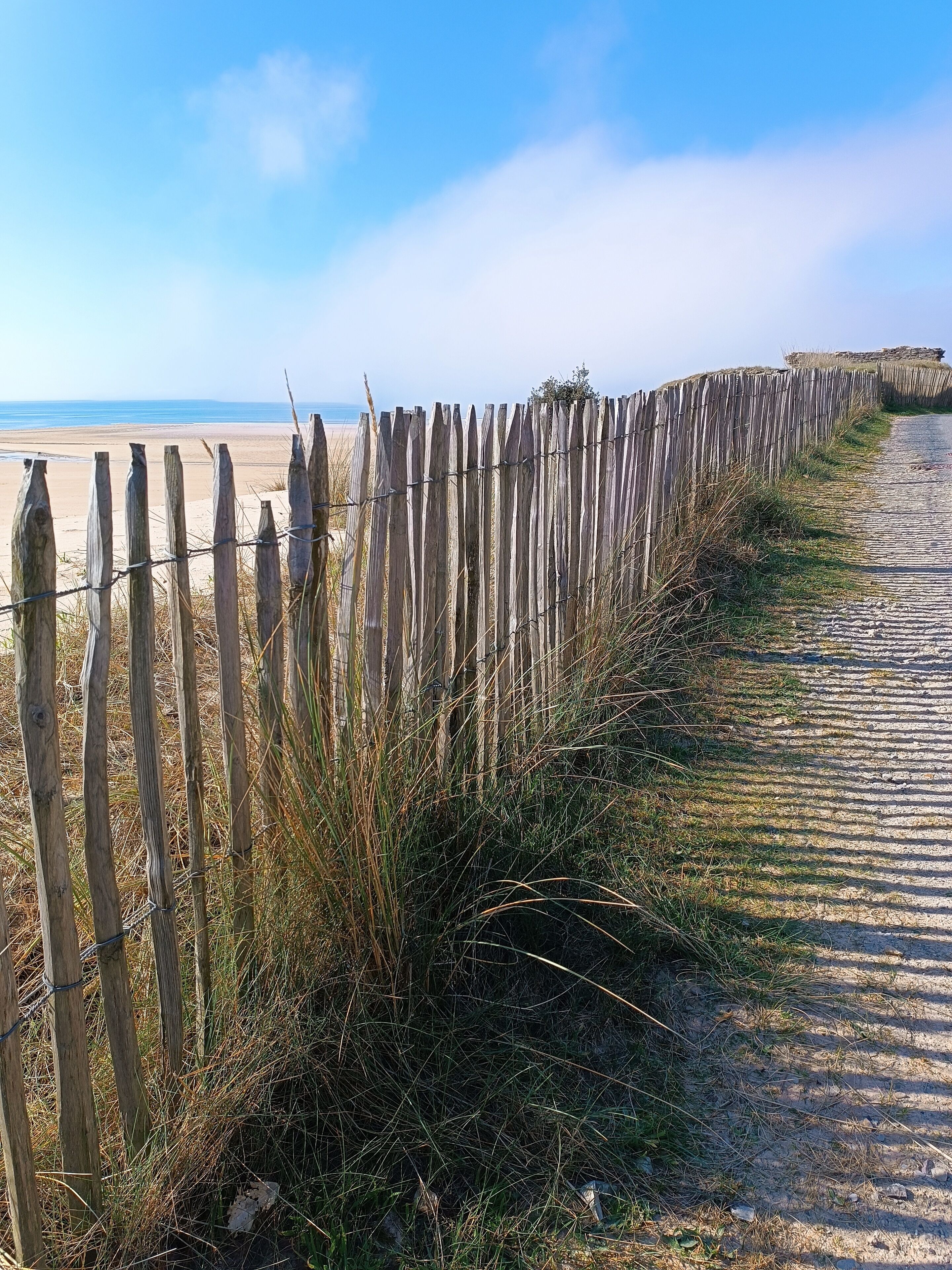 Una tanca de fusta al costat d'un camí de platja.