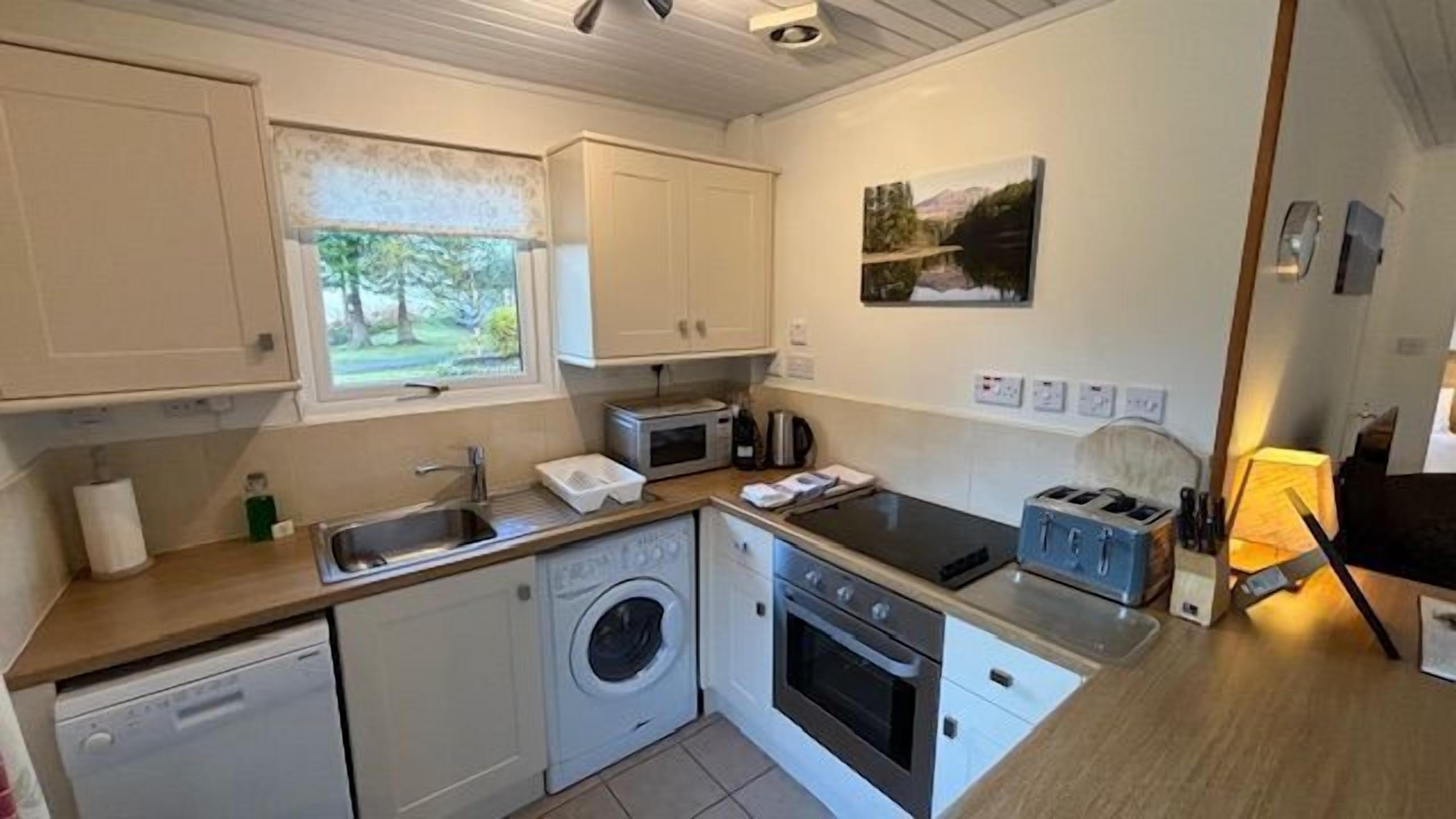 A compact kitchen with a washing machine, microwave, and a small oven.