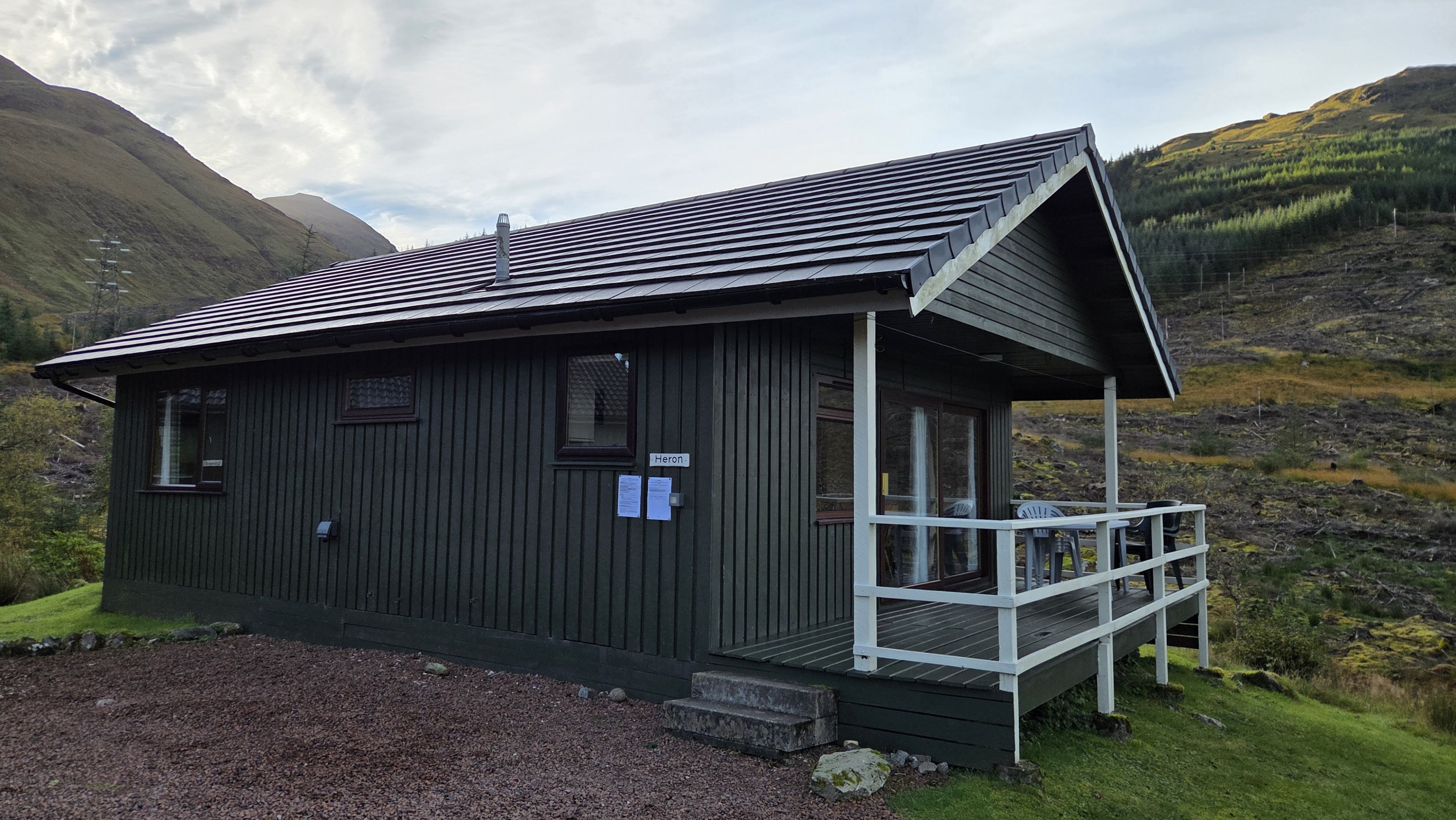 A small, dark wooden cabin with a sloped roof and a covered porch.
