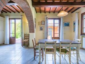 A dining area with a large table and six chairs, a brick chimney, and a view of the outside through open doors. - Lovely apartment in villa for 10 people with WIFI, hot tub, A/C, private pool, TV and pets allowed (Fucecchio)