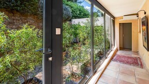 Un couloir moderne doté de grandes portes vitrées donnant sur un jardin.