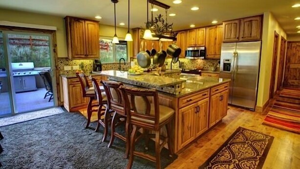 A kitchen with wooden cabinets, a central island with bar stools, stainless steel appliances, and pendant lighting.