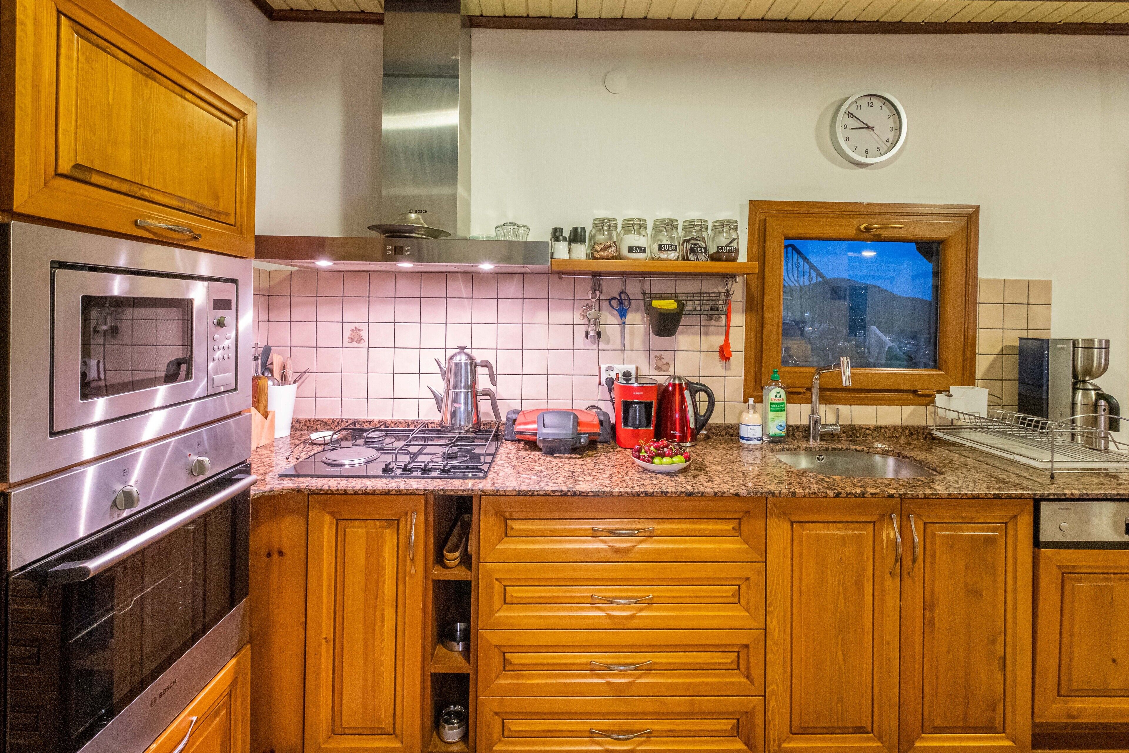 A kitchen with wooden cabinets, stainless steel appliances, a tiled backsplash, and a window with a view.