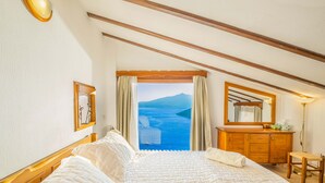 A bedroom with a large bed, wooden headboard, a wooden dresser, a mirror, and a view of the sea and mountains. - Secluded & Luxurious Mediterranean Villa w/ Heated Infinity Pool & Kids' Pool (Kalkan)