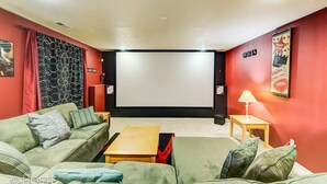 Ein Heimkino mit einer großen Leinwand, roten Wänden und grünen Sofas.
