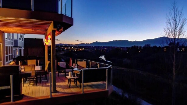 Ein modernes Gebäude mit einer Terrasse mit Blick auf eine Stadtlandschaft und Berge.