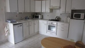 A kitchen with white cabinets, a microwave, a dishwasher, and a wooden table.