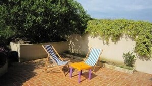 A patio with two striped lounge chairs and a small table.