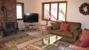 A living room with a fireplace, a television, a sofa, and a coffee table. - Killington ski house (Stockbridge)