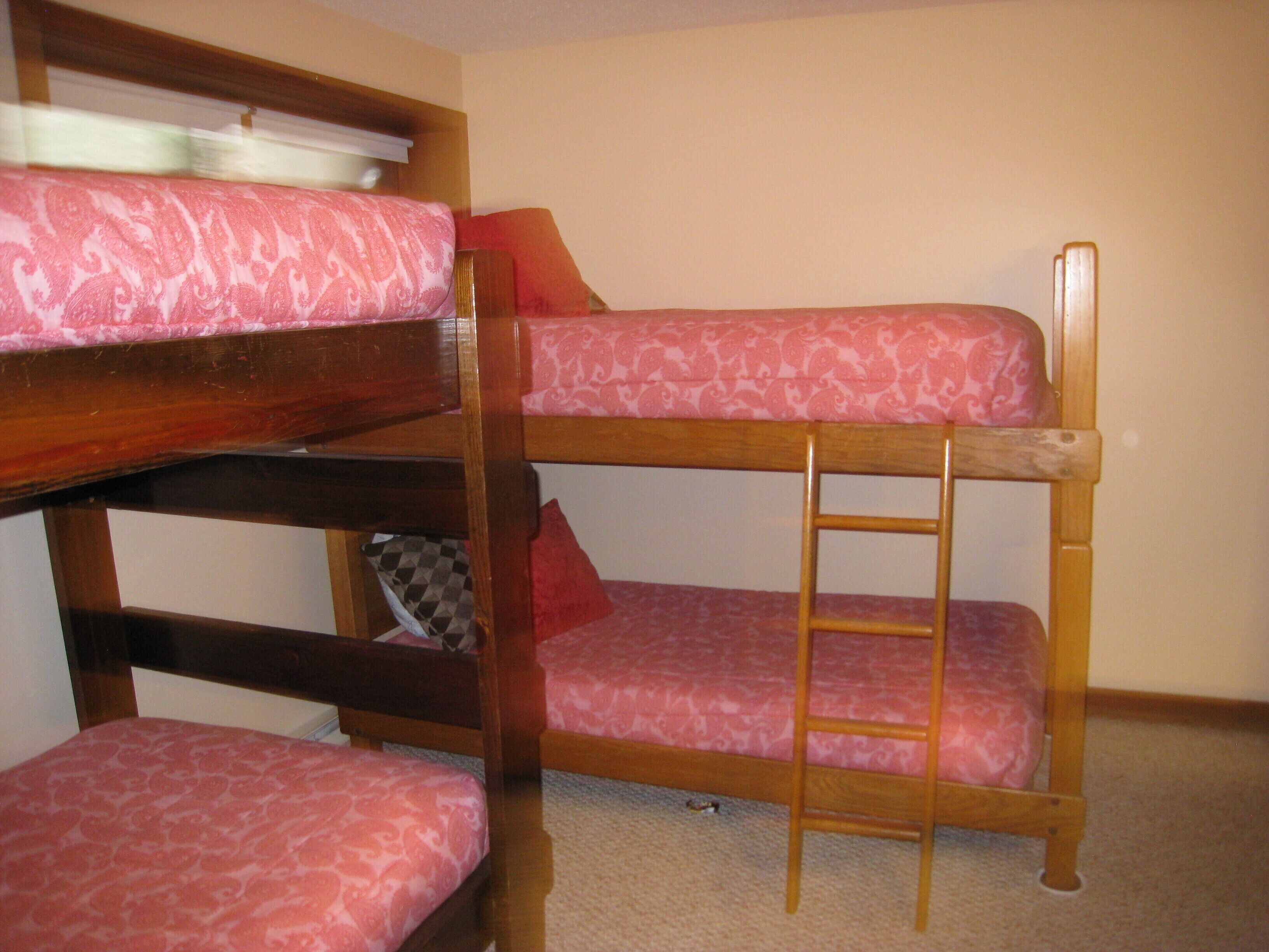 A bunk bed with a ladder, a checkered pillow, and a red pillow.