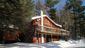 A wooden cabin with a balcony, surrounded by snow and trees. - Killington ski house (Stockbridge)