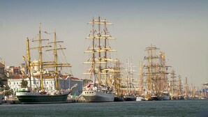 Un puerto con varios barcos de gran tamaño amarrados, rodeado de edificios.