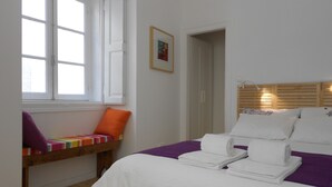 Un dormitorio con cama, ventana, mesita de noche y puerta.