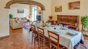 A dining area with a piano, a TV, and a cozy living room with a sofa and a TV. - Private Villa with WIFI, private pool, TV, balcony, pets allowed, panoramic view, close to Cortona (Castiglion Fiorentino)