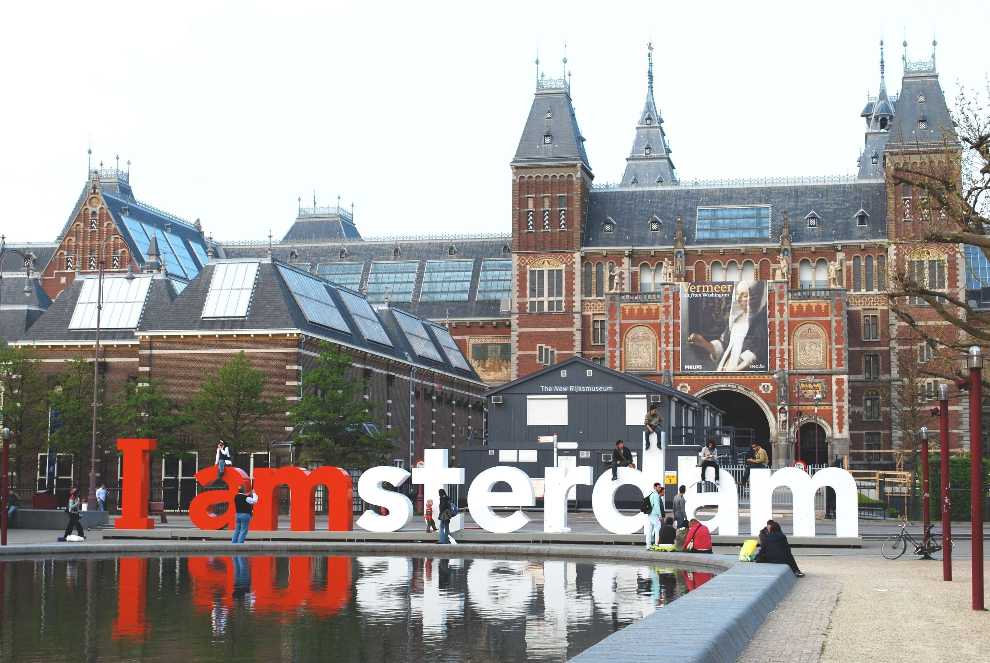 A historic building with large 'I Amsterdam' letters in front of it.
