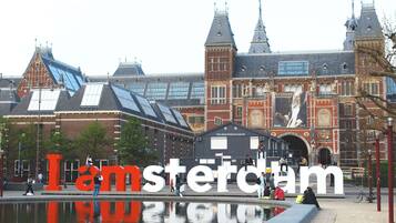 A historic building with large 'I Amsterdam' letters in front of it.
