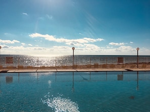 View of the pool and Atlantic Ocean beach with comfortable lounge chairs.