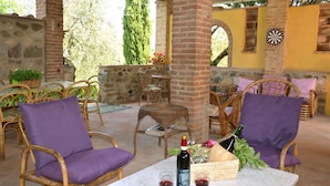 An outdoor patio with wicker chairs and a table set with wine glasses and a bottle. - Wonderful private villa for 9 guests with private pool, WIFI, TV, patio and pets allowed (Montopoli In Val D'arno)