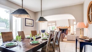Un comedor con una mesa de madera, sillas de mimbre e iluminación colgante.