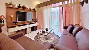 Una sala de estar moderna con una televisión de pantalla plana, un juego de sofá, una mesa de centro y un ventilador de techo.