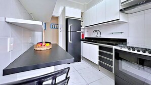 Una cocina moderna con armarios blancos, encimera negra y estufa a gas integrada.