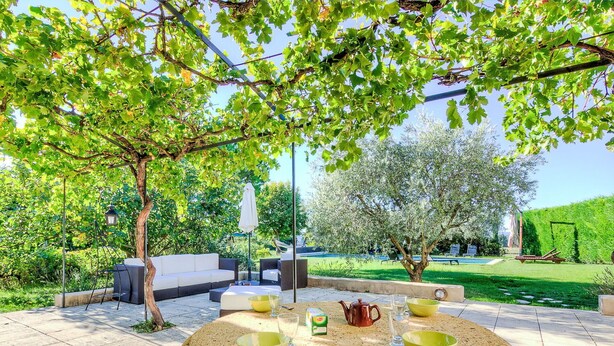 A round stone table with green bowls, a teapot, and a glass set in a garden with outdoor seating and a pool. - Wonderful private villa for 9 guests with private pool, WIFI, TV and terrace (Cucuron)