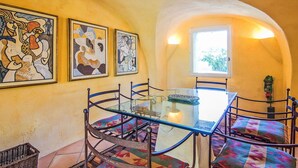A dining area with a glass table, metal chairs, and colorful cushions. There are three framed artworks on the wall. - Wonderful private villa for 9 guests with private pool, WIFI, TV and terrace (Cucuron)