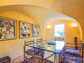 A dining area with a glass table, metal chairs, and colorful cushions. There are three framed artworks on the wall. - Wonderful private villa for 9 guests with private pool, WIFI, TV and terrace (Cucuron)