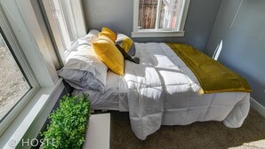 A small, cozy bedroom with a bed, a window, and a plant. - Downtown Cottage with Netflix TV near Old Colorado (Colorado Springs)