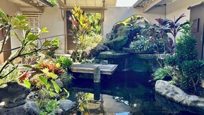 Un jardin paisible avec un étang, des rochers et différentes espèces de plantes.