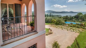 A balcony with a view of a lake, mountains, and a swimming pool.