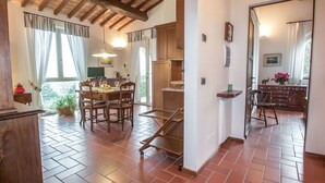 A spacious kitchen with a dining area, wooden cabinets, and a tiled floor.