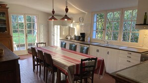 A kitchen with a dining table, chairs, and a large window. - Mansion of an old farm, cottage in France, quiet and romantic stay in the Gers (Gavarret-Sur-Aulouste)