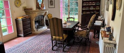 Una sala da pranzo con camino, tappeto decorato e libreria piena di piatti.