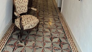 A hallway with patterned floor tiles, a wooden chair, and wall-mounted lamps. - Mansion of an old farm, cottage in France, quiet and romantic stay in the Gers (Gavarret-Sur-Aulouste)