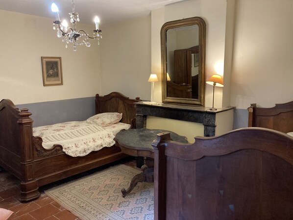 Un dormitorio con una cama de madera, un mesita de noche, un espejo y una araña.
