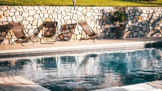 Una piscina con paredes de piedra y sillas.