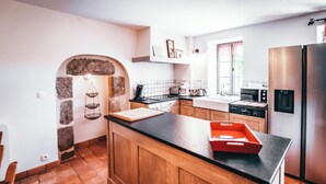 Una cocina moderna con armarios de madera, encimera negra y refrigerador de acero inoxidable.