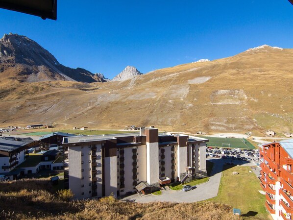 A modern hotel with multiple floors, a parking area, and a view of a mountainous landscape. - Beautiful apartment for 6 guests with WIFI, TV and balcony (Les Boisses)