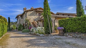 A stone house with a gravel driveway, surrounded by greenery and a clear blue sky. - Cosy apartment for 6 guests with pool, WIFI, TV, patio, pets allowed and panoramic view (Allerona)