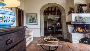 A rustic interior with a fireplace, a dining area, and a kitchen visible through an archway. - Cosy apartment for 6 guests with pool, WIFI, TV, patio, pets allowed and panoramic view (Allerona)