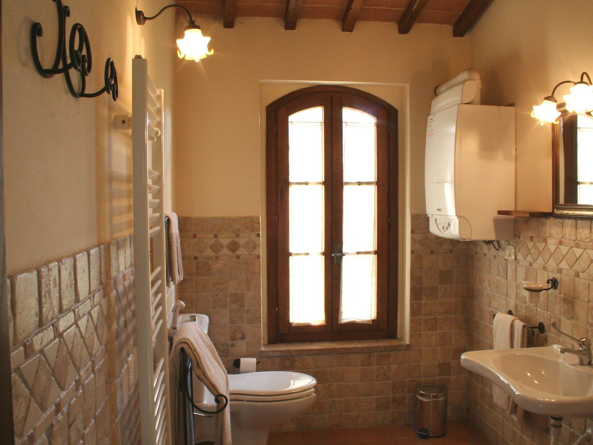 Une salle de bain équipée de toilettes, d’un lavabo et d’une fenêtre avec un cadre en bois.