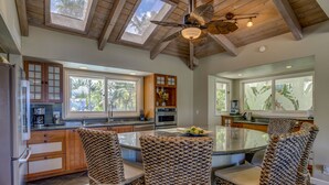 A modern kitchen with a central island, wooden cabinetry, and large windows.