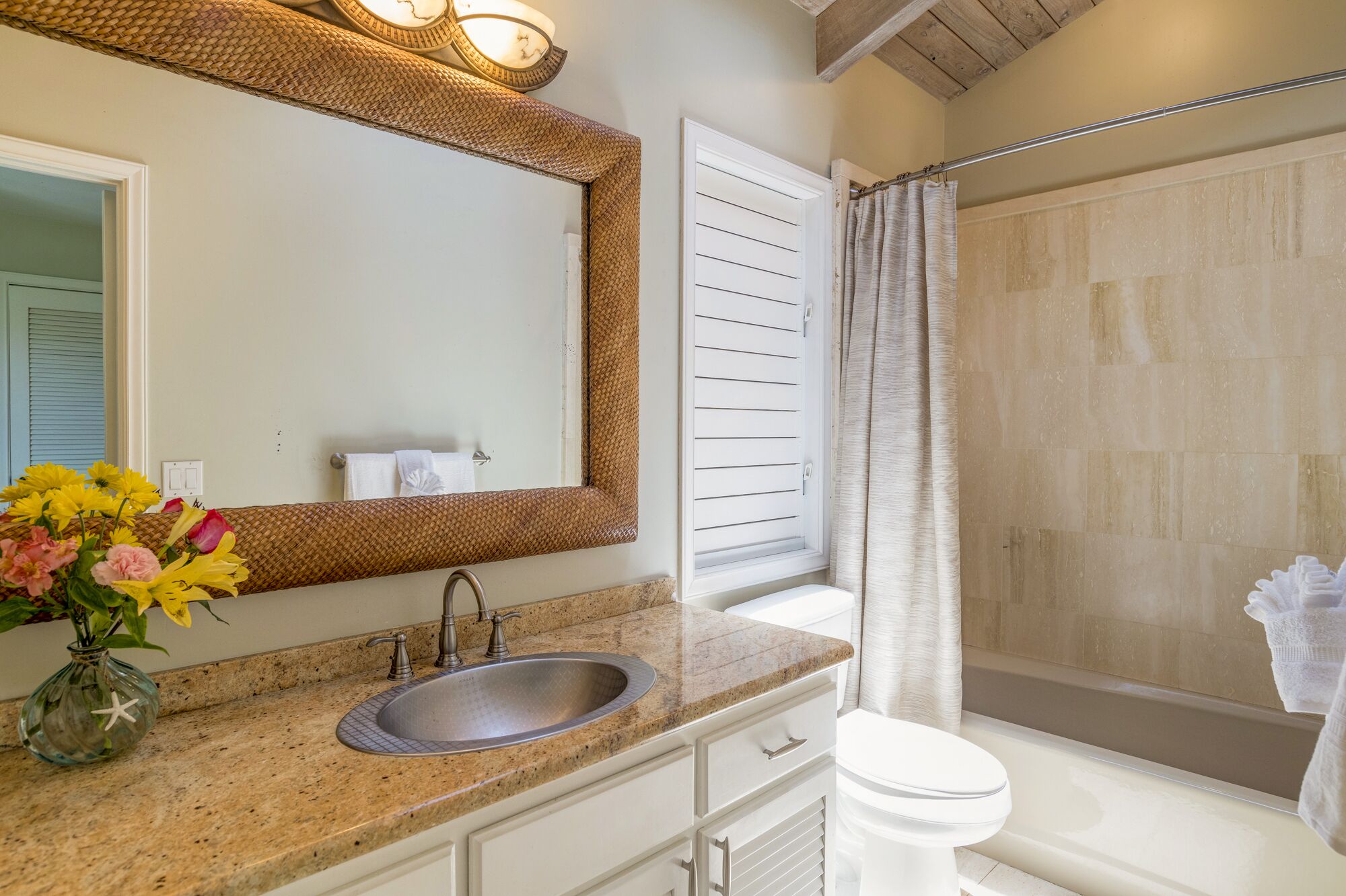A bathroom with a sink, mirror, and shower.