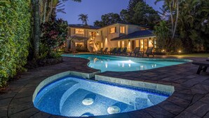 A two-story house with a swimming pool and lounge chairs.