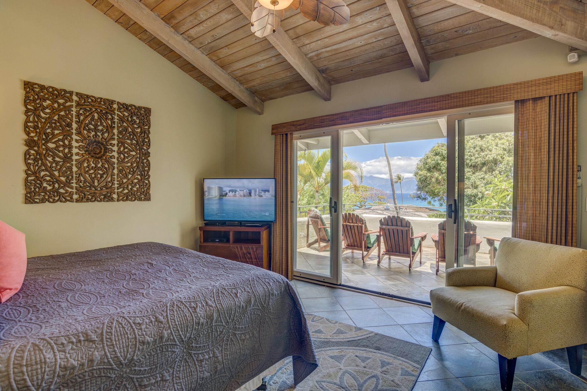 A bedroom with a bed, a TV, and a view of the outdoors.