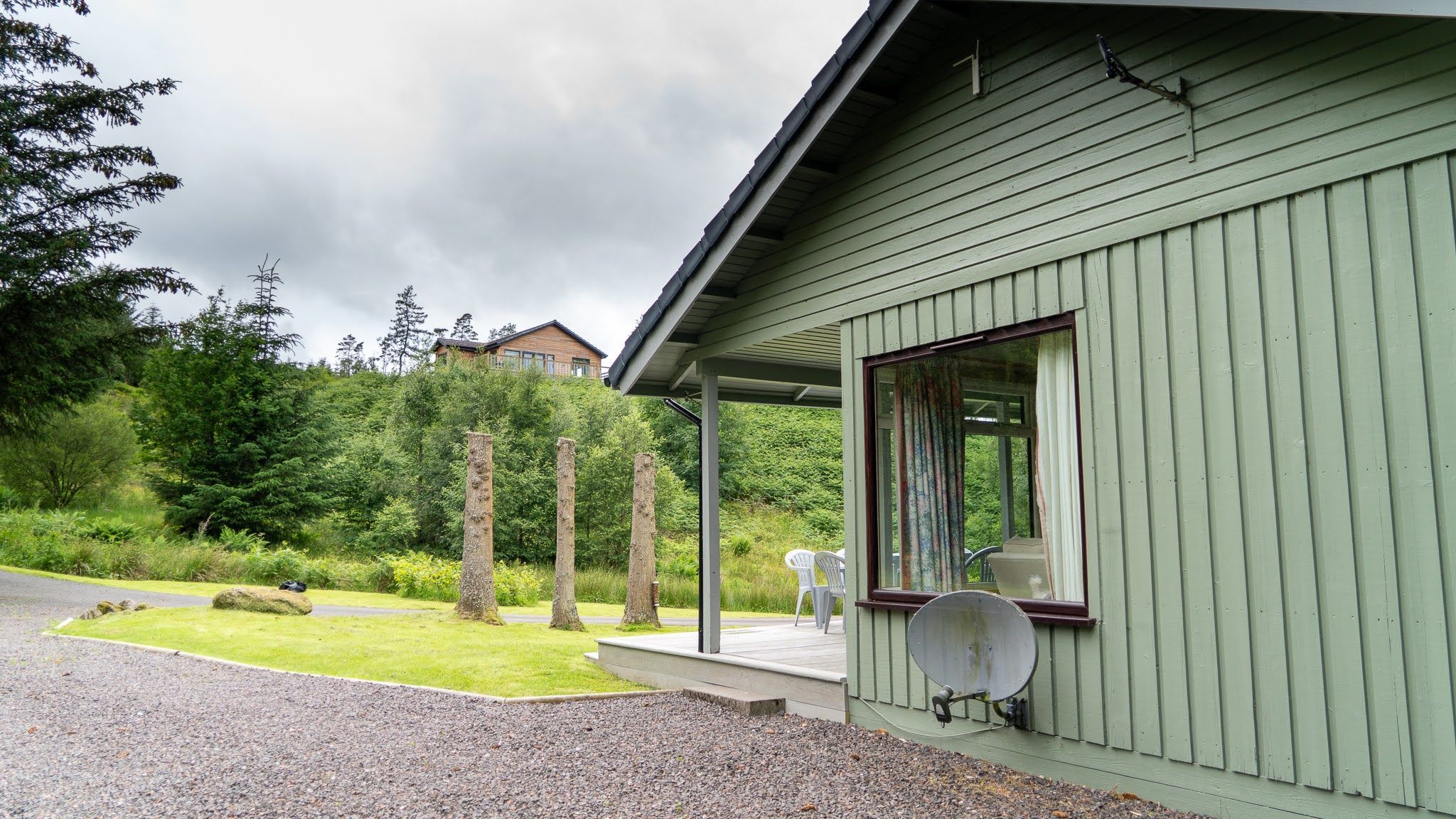 A house with a covered porch, a satellite dish, and a grassy yard.
