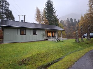 Un bâtiment d’un seul étage, doté d’un porche couvert et d’un petit espace extérieur aménagé pour s’asseoir.