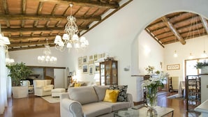 A spacious living room with a high ceiling, a fireplace, and a dining area with a table and chairs.