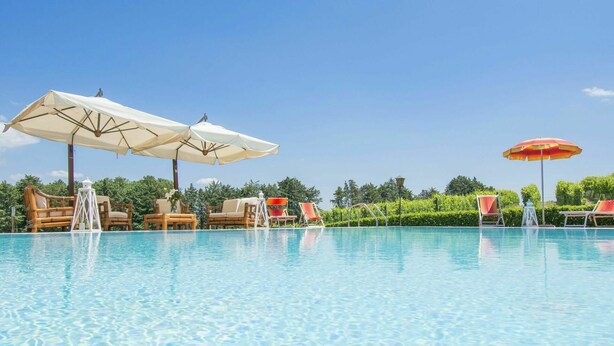 A clear swimming pool with lounge chairs and umbrellas.